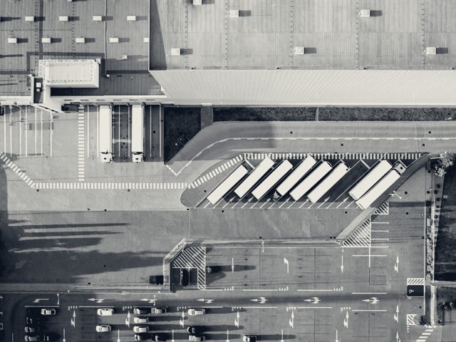 Aerial view looking straight down on a distribution centre, its dock apron and a row of parked trucks